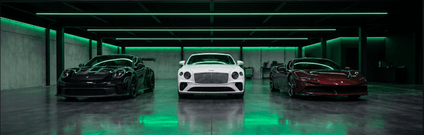 Three luxury cars, a black sports car, white Bentley and red coupe, in a green-lit garage