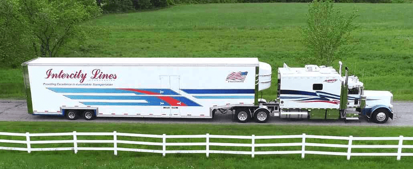 White Intercity Lines enclosed car transport trailer parked beside a white fence on green grass