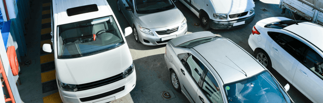 White van and sedans parked tightly together, viewed from above