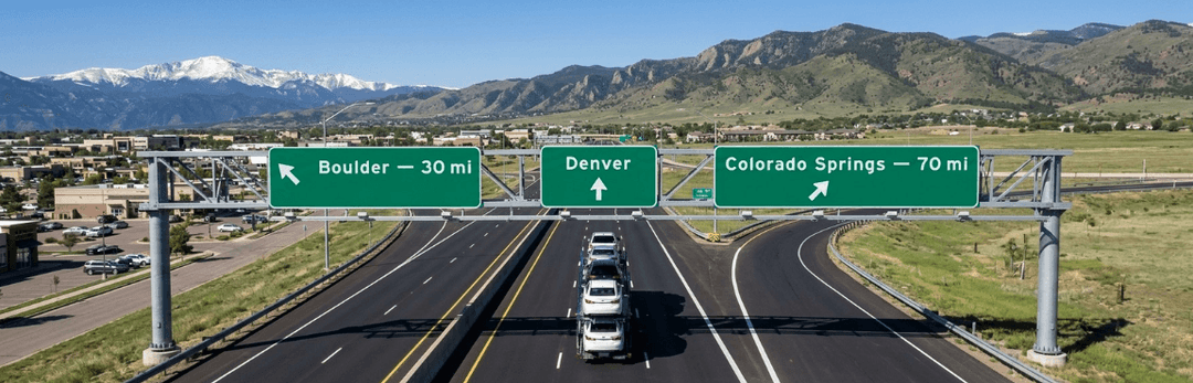 Colorado highway with overhead signs for Boulder 30 mi, Denver and Colorado Springs 70 mi below mountains