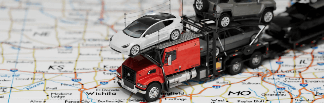 Toy red car carrier loaded with model cars resting on a printed road map, illustrating Massachusetts shipping costs