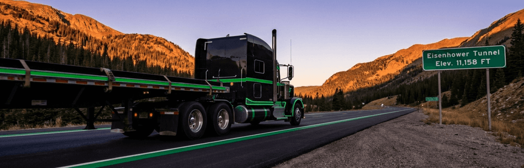Car carrier truck on a mountain highway passing an Eisenhower Tunnel sign at 11,158 ft elevation