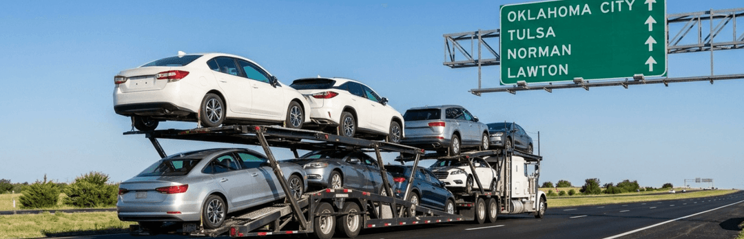 Loaded car carrier on a highway under a sign for Oklahoma City, Tulsa, Norman and Lawton
