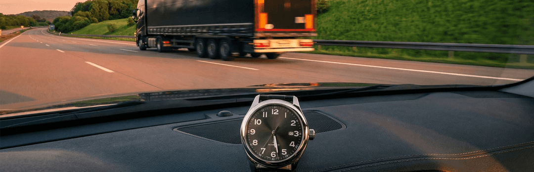 Car dashboard with an analog watch as a semi truck passes on a green Texas to Georgia highway