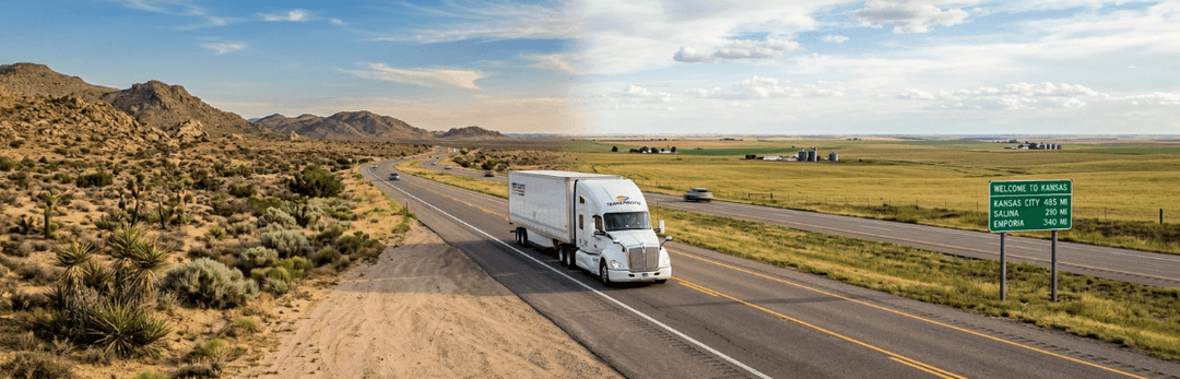 White semi truck on a desert highway on the California to Kansas corridor under a wide blue sky
