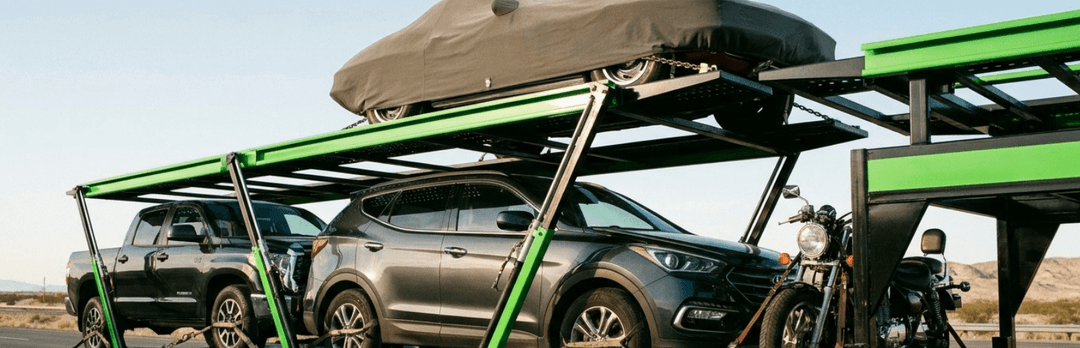 Car carrier hauling an SUV with a roof box, a pickup truck and a motorcycle on its deck